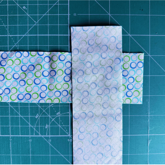 Two quilt binding fabric strips placed right sides together at right angles, ready to be joined diagonally.