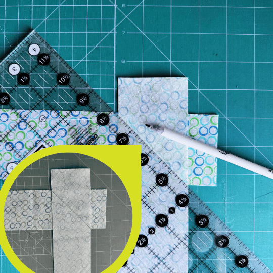 Quilting ruler and pencil used to draw a diagonal sewing line across two quilt binding strips placed right sides together.