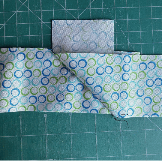 Joined quilt binding strips opened out to check the diagonal seam is correct before trimming away the excess fabric.