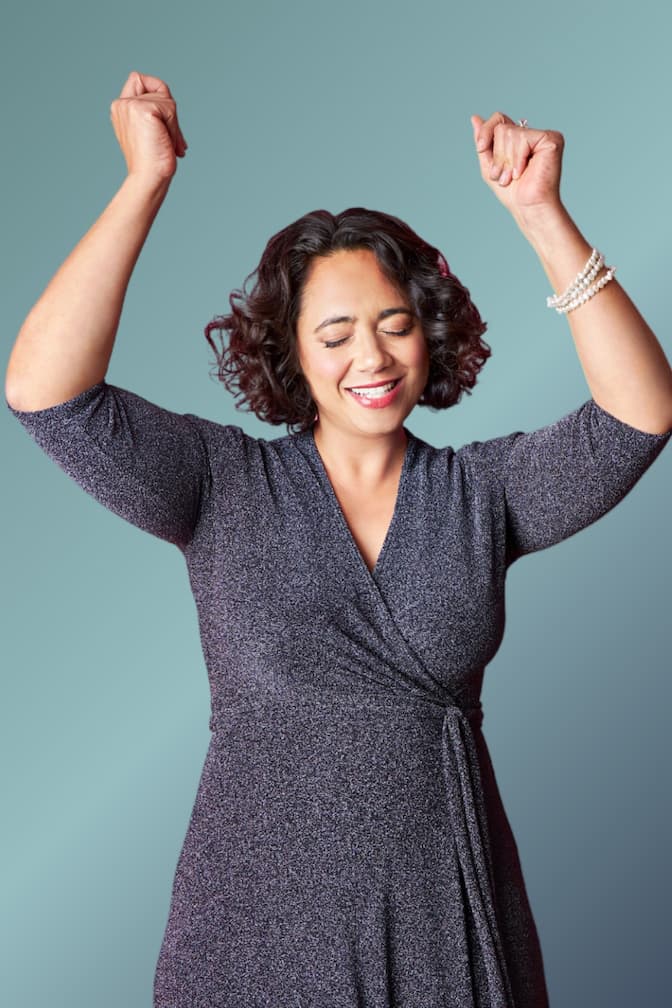 Alena Bennett in sparkly blue V-neck dress, hands raised up